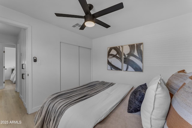 bedroom with a ceiling fan, visible vents, light wood-style flooring, and a closet