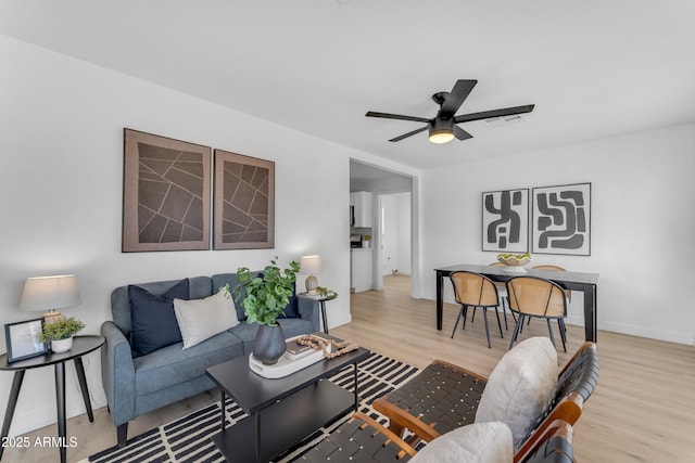 living room with baseboards, ceiling fan, wood finished floors, and visible vents