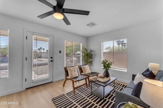 living area featuring light wood finished floors, visible vents, baseboards, and ceiling fan