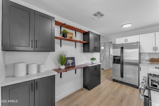 kitchen with visible vents, open shelves, baseboards, light wood finished floors, and appliances with stainless steel finishes