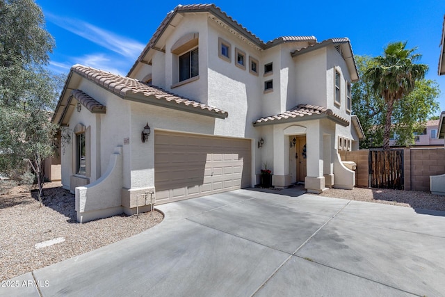mediterranean / spanish house with fence, an attached garage, stucco siding, a tiled roof, and driveway