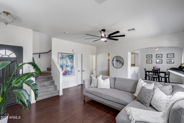 living area featuring visible vents, a ceiling fan, wood finished floors, stairway, and arched walkways