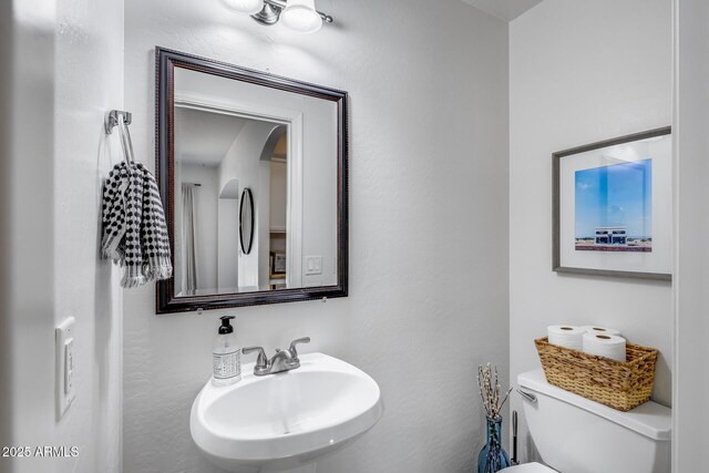 half bathroom featuring toilet and a sink