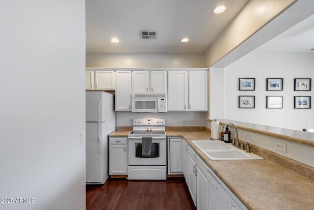 kitchen featuring white cabinets, a sink, white appliances, light countertops, and visible vents