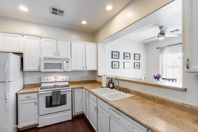 kitchen featuring visible vents, a sink, white appliances, and light countertops