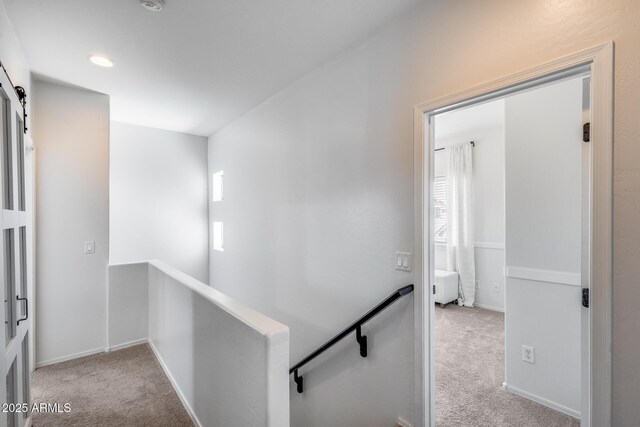 hallway with carpet floors, baseboards, and an upstairs landing