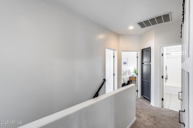 hall with carpet floors, visible vents, recessed lighting, and an upstairs landing