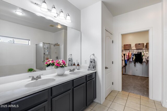 full bath featuring a sink, tile patterned flooring, a shower stall, and double vanity