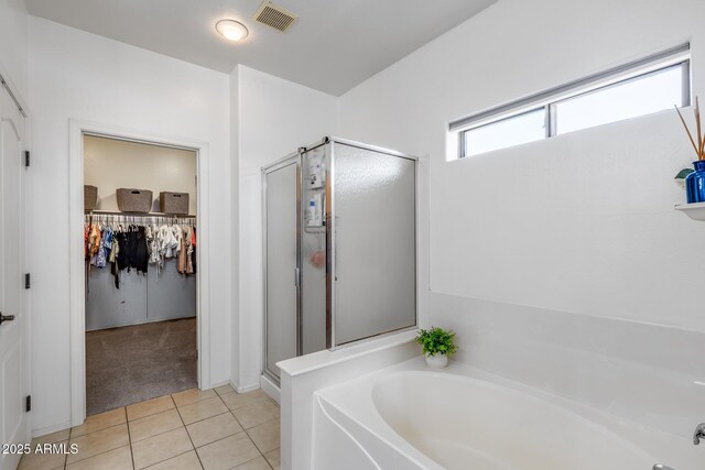 full bath with tile patterned floors, a shower stall, a spacious closet, visible vents, and a garden tub