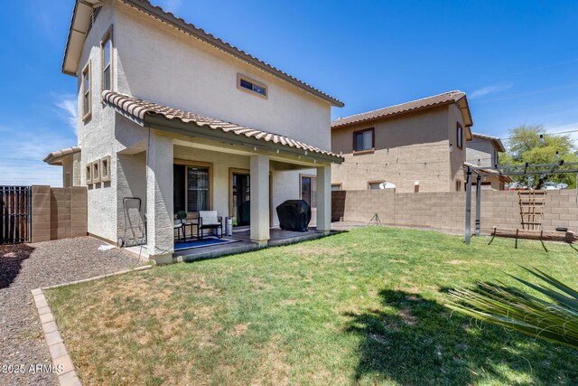 back of property featuring a lawn, a fenced backyard, stucco siding, and a tile roof