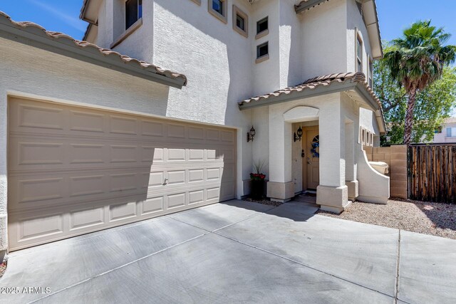view of front of home with fence, stucco siding, driveway, and a tiled roof