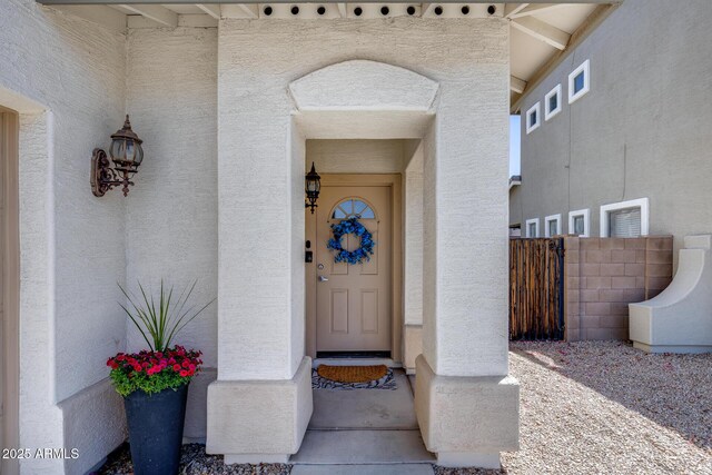 entrance to property featuring fence and stucco siding