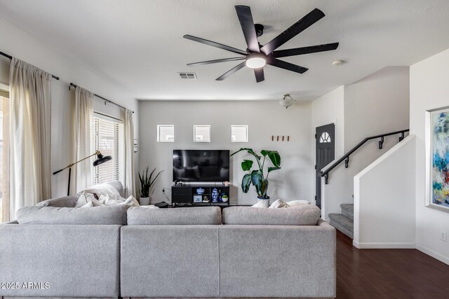 living area featuring ceiling fan, visible vents, dark wood finished floors, baseboards, and stairs