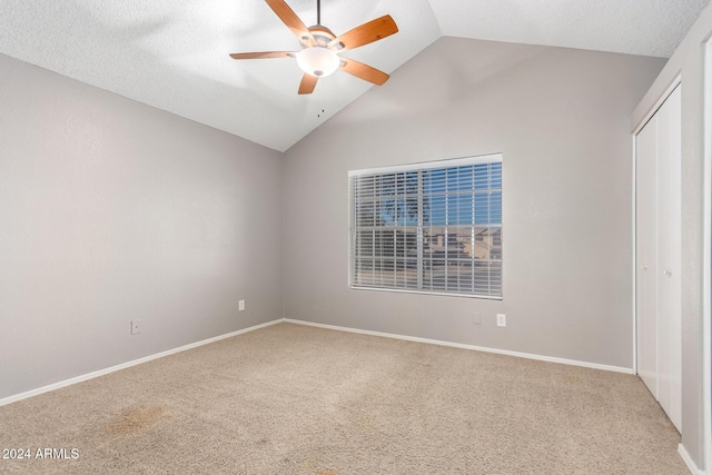 unfurnished bedroom featuring ceiling fan, carpet floors, a textured ceiling, and vaulted ceiling