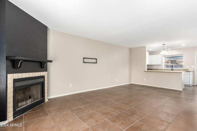 unfurnished living room with a large fireplace, tile patterned floors, and sink