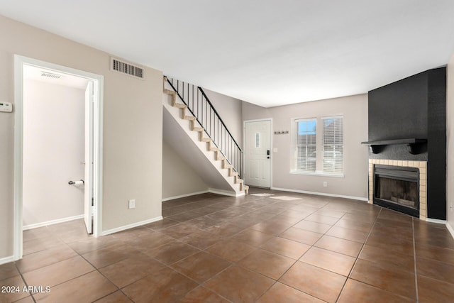 unfurnished living room featuring a large fireplace and dark tile patterned floors