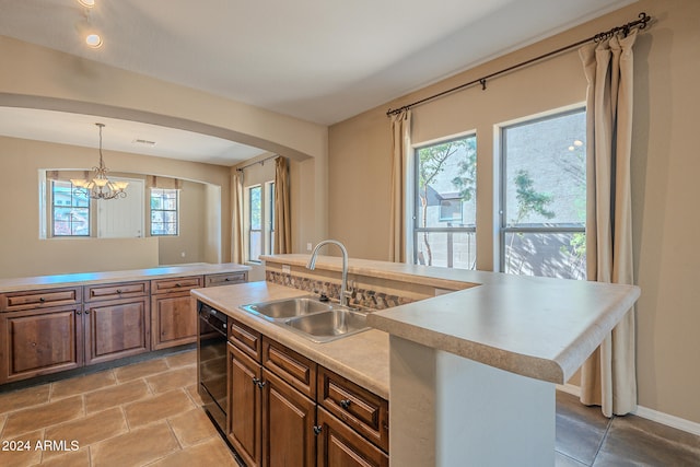 kitchen with a center island with sink, a healthy amount of sunlight, sink, and pendant lighting