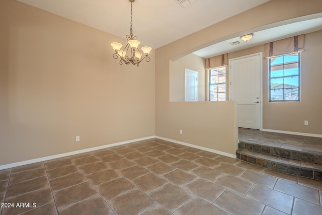 empty room with a chandelier and tile patterned flooring