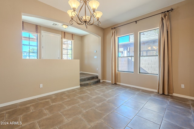 spare room with tile patterned flooring and a chandelier