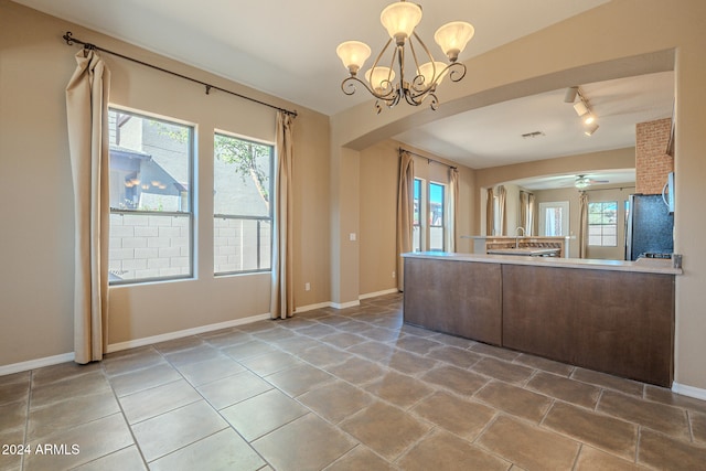 kitchen featuring tile patterned flooring, plenty of natural light, stainless steel fridge, and hanging light fixtures