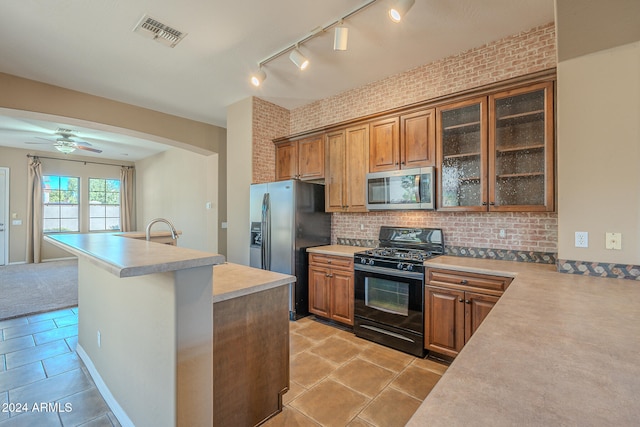 kitchen with light tile patterned flooring, brick wall, and appliances with stainless steel finishes