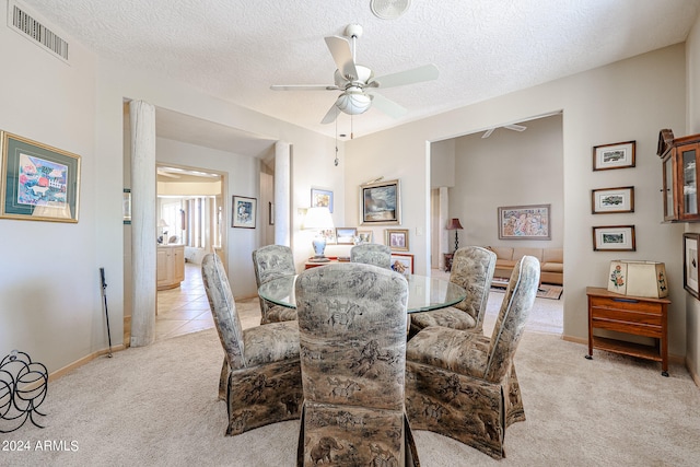 dining space featuring light carpet, a textured ceiling, and ceiling fan