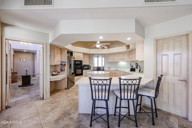 kitchen featuring black appliances, sink, ceiling fan, kitchen peninsula, and a breakfast bar area