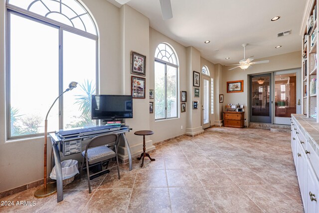 interior space with white cabinets, tile counters, a wealth of natural light, and ceiling fan