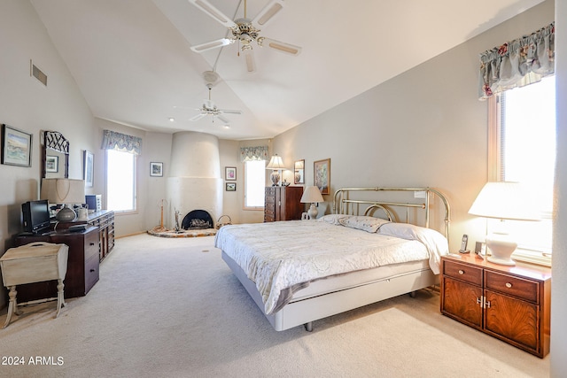 bedroom featuring light carpet, a large fireplace, vaulted ceiling, and ceiling fan