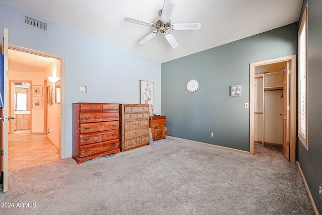 bedroom with a walk in closet, ceiling fan, a closet, and light carpet