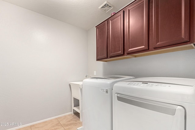 washroom featuring light tile patterned floors, washing machine and dryer, and cabinets