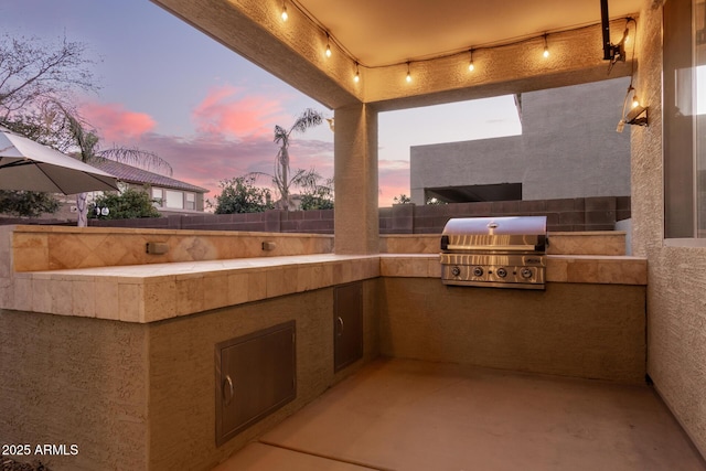 patio terrace at dusk with grilling area and an outdoor kitchen