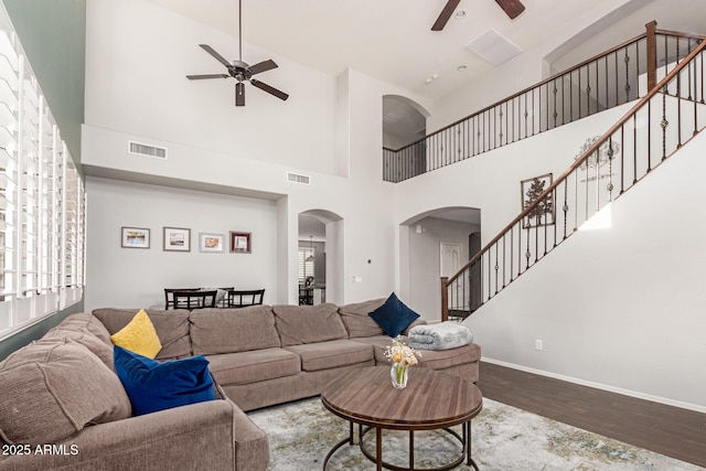 living room featuring ceiling fan, hardwood / wood-style floors, and a towering ceiling