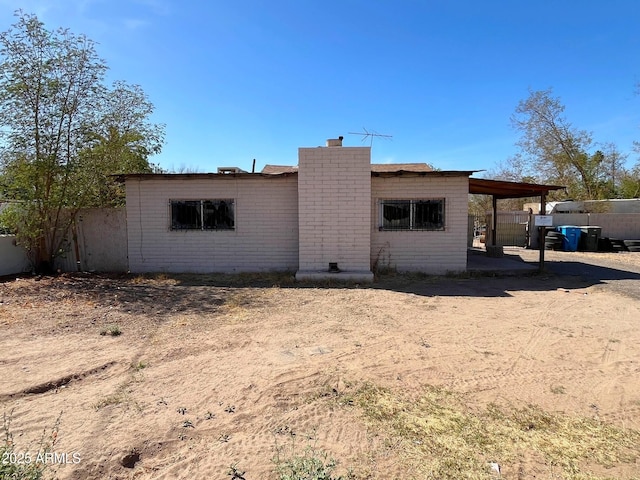 view of front facade featuring a carport, a chimney, and fence