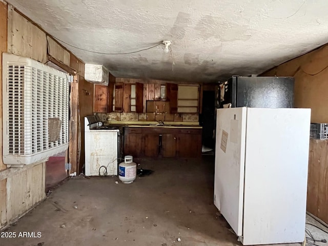 kitchen featuring washer / dryer, a textured ceiling, a sink, and freestanding refrigerator