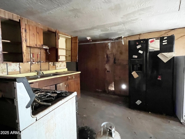 kitchen with open shelves, brown cabinetry, white range with gas cooktop, concrete flooring, and black fridge