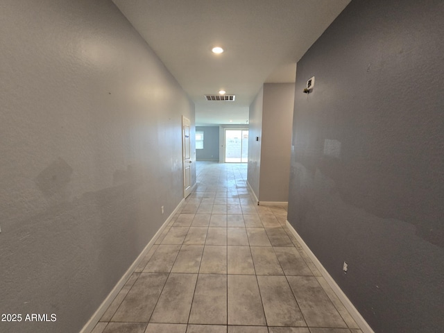 hallway featuring light tile patterned floors, visible vents, and baseboards