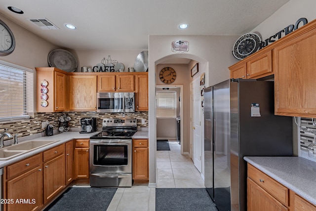 kitchen featuring backsplash, visible vents, light tile patterned floors, arched walkways, and appliances with stainless steel finishes