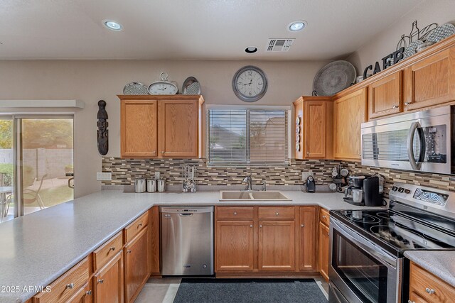 kitchen with backsplash, visible vents, appliances with stainless steel finishes, and a sink