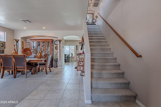 stairway featuring arched walkways, a healthy amount of sunlight, and visible vents