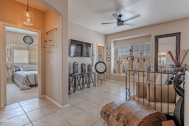 entryway with light tile patterned floors, baseboards, arched walkways, and ceiling fan