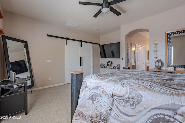 bedroom with a barn door, visible vents, light carpet, arched walkways, and baseboards
