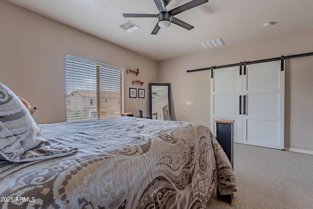 bedroom featuring a barn door, a ceiling fan, carpet flooring, and visible vents