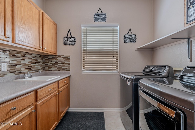 laundry room featuring a sink, separate washer and dryer, light tile patterned floors, cabinet space, and baseboards