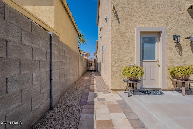 view of side of property with fence, a gate, and stucco siding