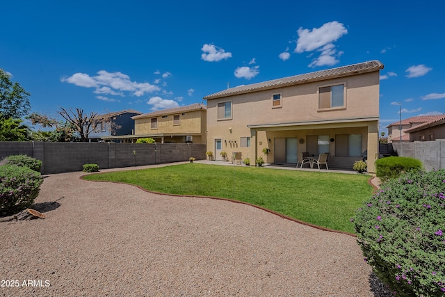 back of property featuring a fenced backyard, a yard, a patio, and stucco siding