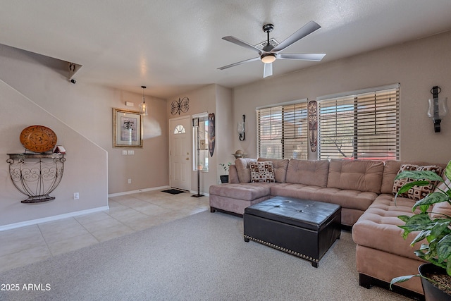 carpeted living area with baseboards, a ceiling fan, and tile patterned floors