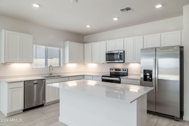 kitchen with light hardwood / wood-style flooring, a center island, stainless steel appliances, white cabinets, and sink