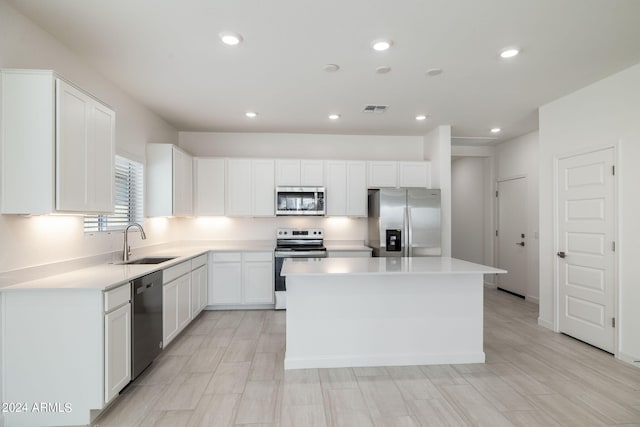 kitchen with a kitchen island, appliances with stainless steel finishes, white cabinetry, and sink