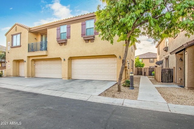 townhome / multi-family property with a tiled roof, driveway, fence, an attached garage, and stucco siding